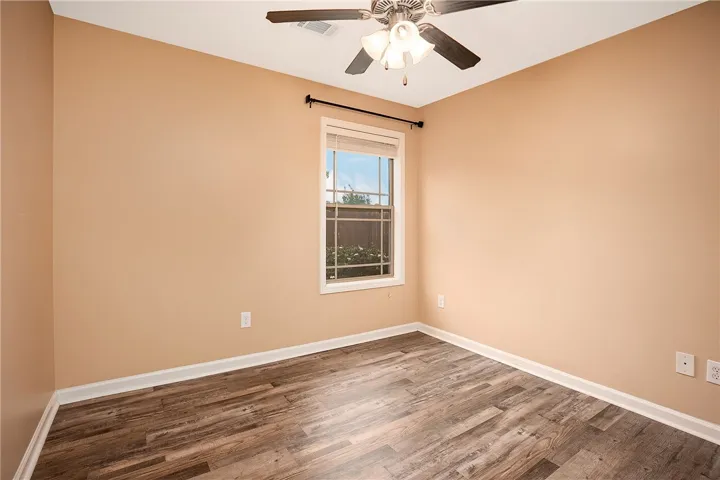 This cozy bedroom features durable wood flooring and a refreshing ceiling fan for ultimate comfort.