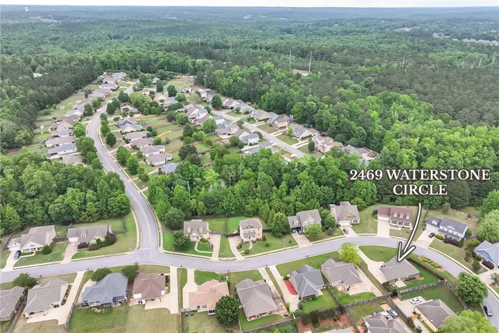 An aerial perspective reveals a vibrant neighborhood nestled among lush, green woodland.