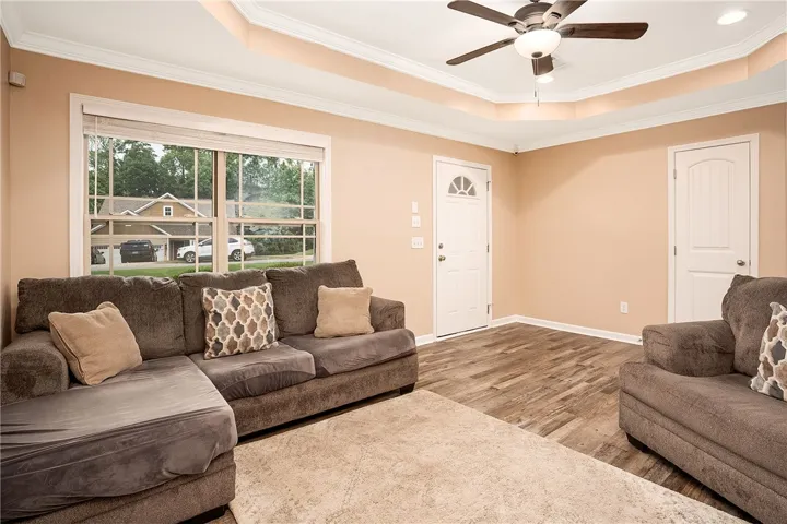 This inviting living room features a ceiling fan, crown molding, and durable laminate flooring.