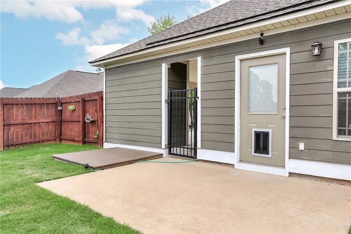 This private backyard features a concrete patio, wooden deck, and secure fencing for outdoor enjoyment.