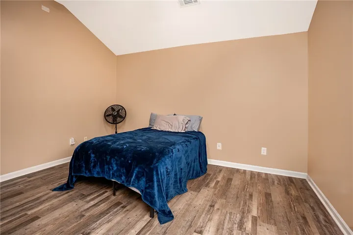 This spacious bedroom features warm-toned walls and durable hardwood flooring, creating a comfortable and inviting atmosphere.