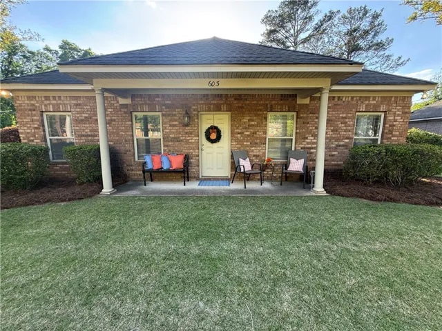 This charming residence features a classic brick exterior and a welcoming covered porch, perfect for outdoor relaxation.