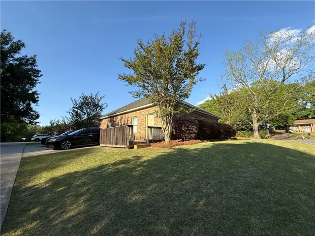 This charming brick home features a cozy deck and a well-maintained lawn.