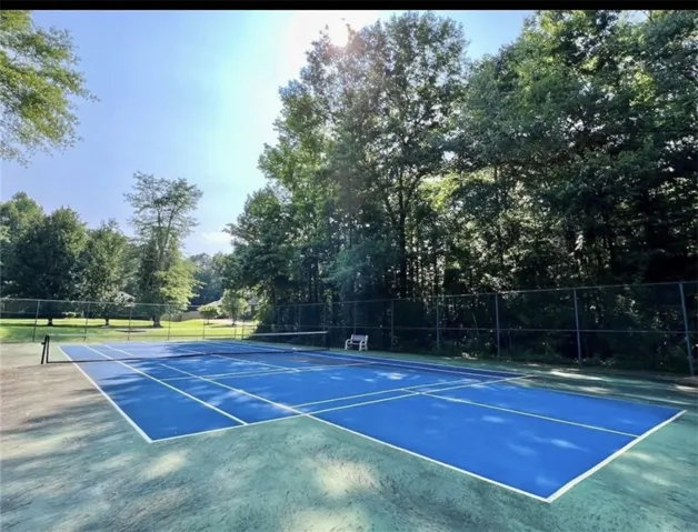 Enjoy outdoor recreation on this pristine tennis court surrounded by lush trees.