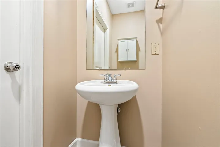 A well-lit powder room offers a pedestal sink and ample wall space.