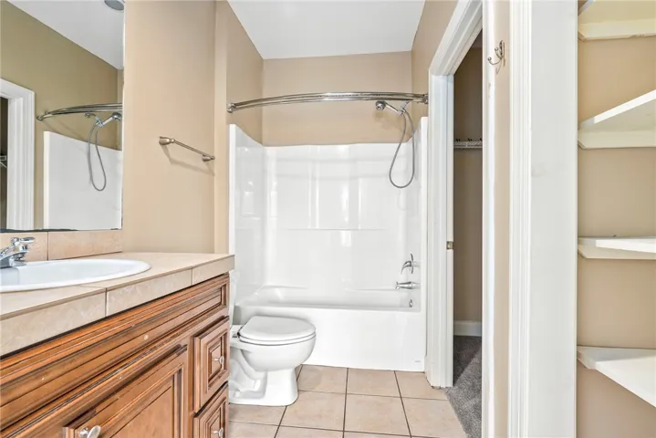 Functional full bathroom featuring a tub-shower combination, single vanity, and tiled flooring.