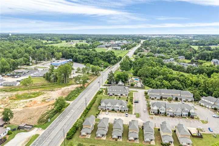 An aerial perspective reveals a vibrant neighborhood with residential buildings nestled among green trees and clear skies.