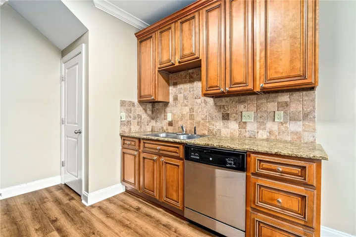 A compact kitchen offers wood cabinetry, granite counters, and modern stainless steel appliances.