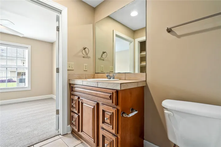 A classic wood vanity with tile counters offers practical elegance in this private bath.