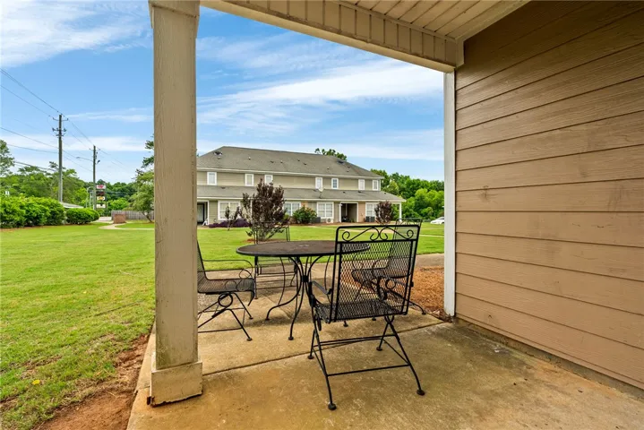 A spacious concrete patio offers a private outdoor retreat with verdant landscaping beyond.