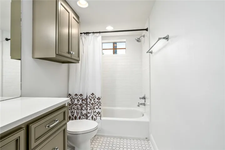 This bright bathroom features a classic bathtub and vanity, offering both style and functionality.