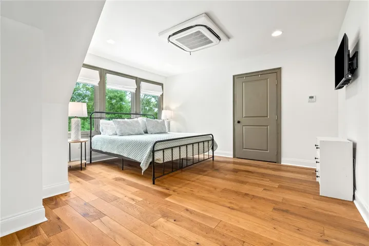 This airy bedroom features abundant natural light and warm hardwood flooring, creating a serene retreat.