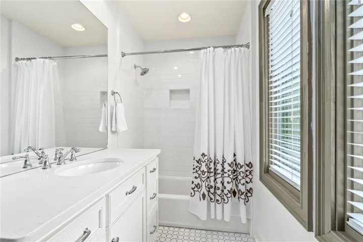 This bright bathroom features a vanity with ample storage and a classic tub and shower combination.