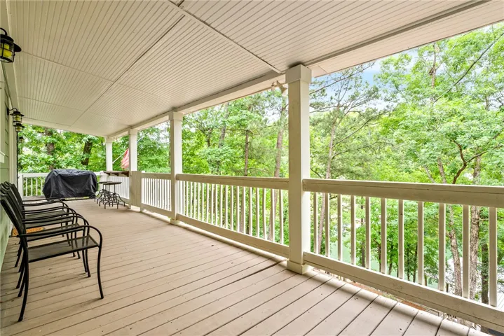This inviting covered porch offers serene outdoor living amidst lush greenery.