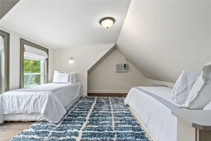 This cozy bedroom features a sloped ceiling and hardwood floors, providing a comfortable and inviting atmosphere.