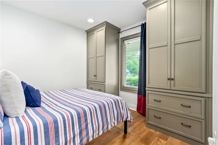 This cozy bedroom features warm wood flooring and ample built-in storage solutions.