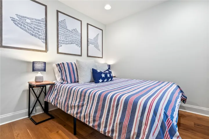 This cozy bedroom offers rich hardwood flooring and bright walls, ideal for serene relaxation.