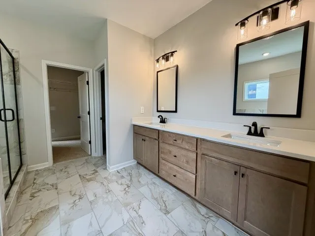 A well-appointed primary bathroom featuring a double vanity, elegant tile flooring, and a glass-enclosed shower.