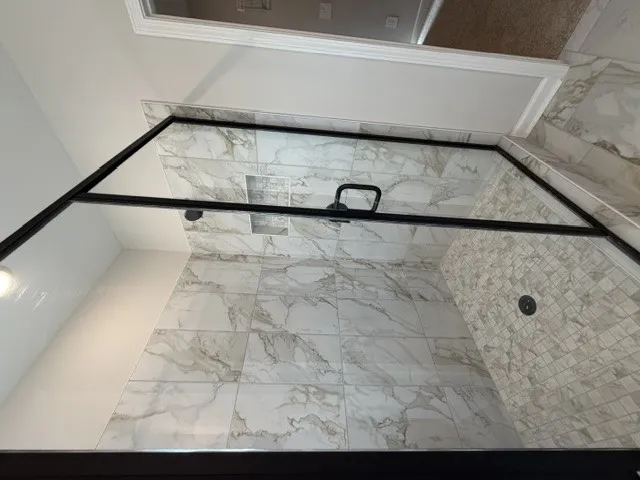 Indulge in this sleek, glass-enclosed shower with pristine tile work and modern fixtures.