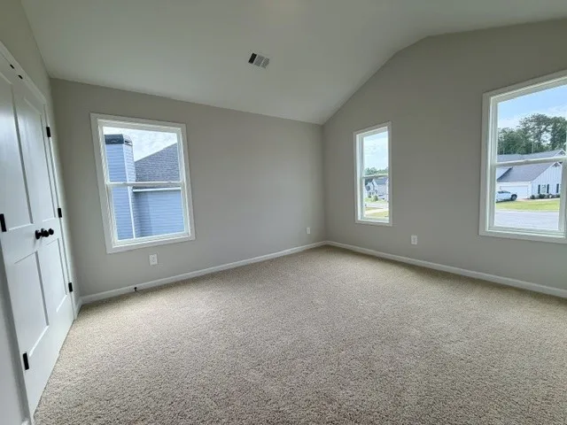 A generously sized bedroom with vaulted ceilings and ample natural light.