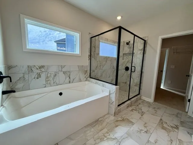 Luxurious bathroom features a spacious soaking tub and a sleek glass-enclosed shower.
