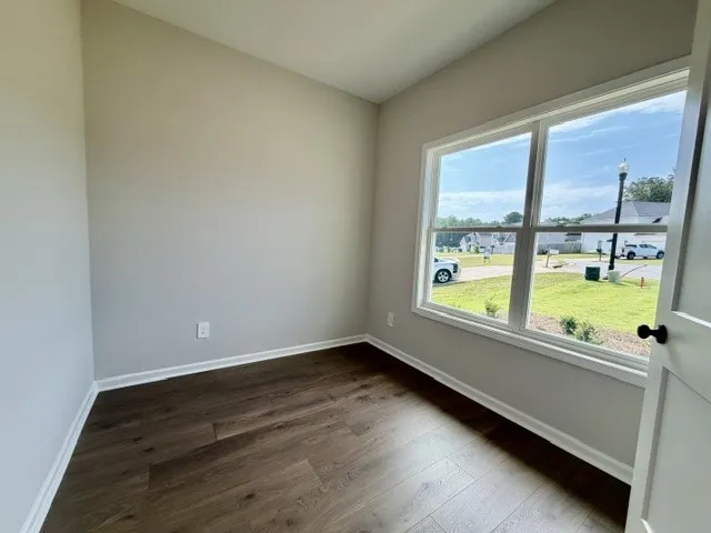 Rich hardwood floors complement the natural light streaming through expansive windows in this welcoming room.