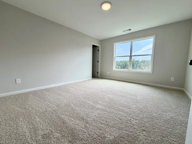 A spacious room offers ample natural light and plush carpeting throughout.