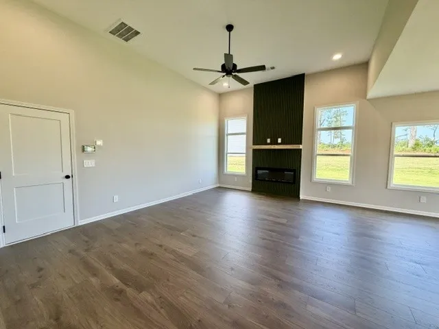 A striking fireplace feature wall grounds this living area, complemented by soaring vaulted ceilings and rich hardwood flooring.