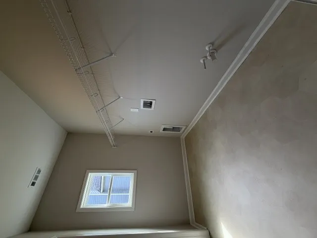 An airy laundry room with high ceilings and practical wire shelving awaits customization.