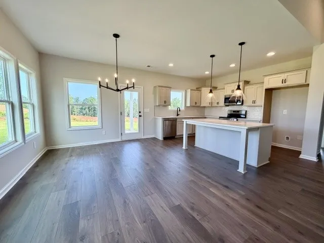 An open-concept layout reveals beautiful flooring and a bright kitchen with a generous island.