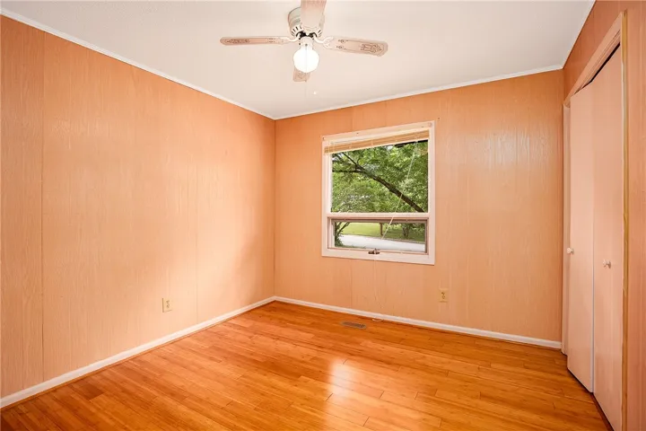 Hardwood flooring and a window offering green views create a serene bedroom retreat.