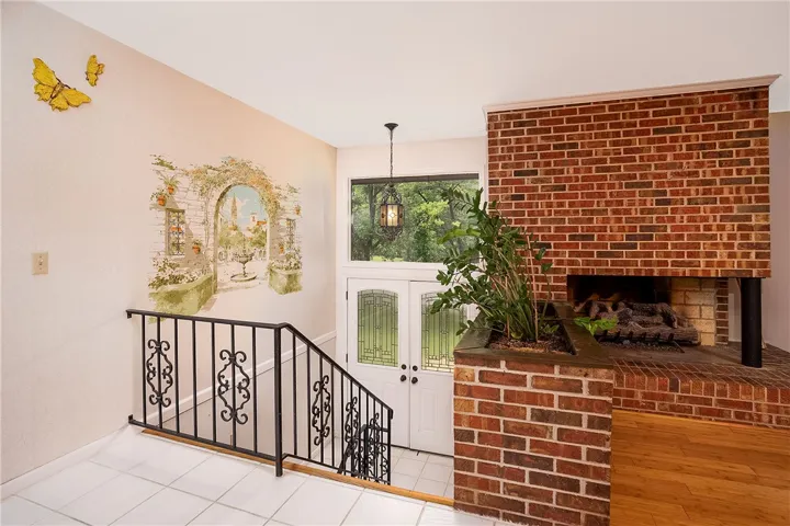 A welcoming entryway boasts leaded glass double doors and a striking brick fireplace with an integrated planter.