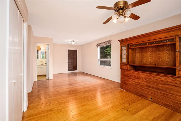 Natural light floods this living area, highlighting warm wood flooring and a classic ceiling fan.