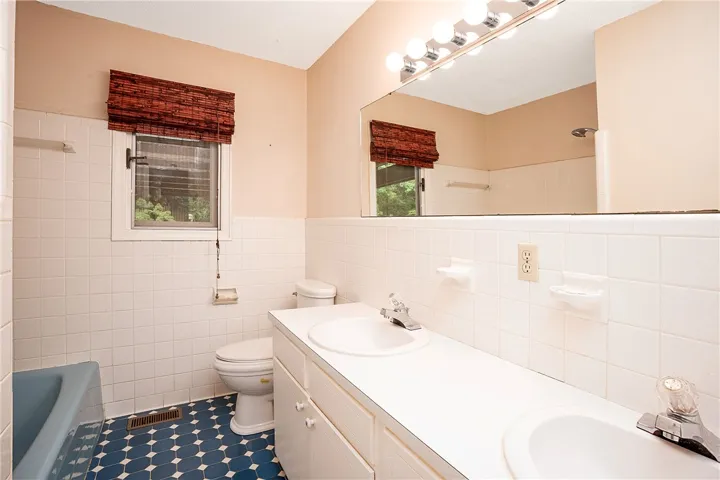 A well-lit bathroom features a spacious vanity and durable tile flooring, providing comfort and functionality.