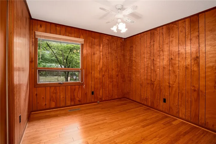 Hardwood floors and warm wood paneling create an inviting bedroom ambiance.