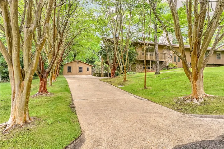 A long, winding driveway leads to a private residence, flanked by lush trees and verdant lawns.