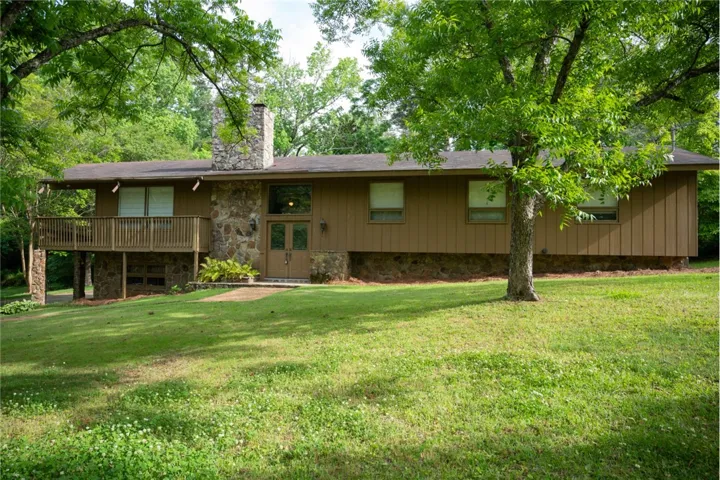 This residence features a wood and stone facade with a spacious deck overlooking the lush landscape.