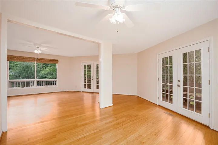 Luminous hardwood floors extend throughout an adaptable living space, offering tranquil views of mature trees.