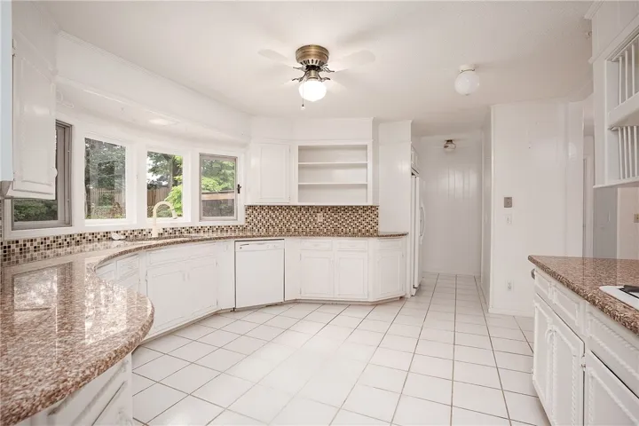 A well-lit kitchen with ample counter space and a pleasant view through bay windows.