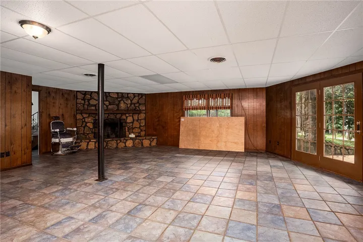 A spacious lower-level room boasts a rustic stone fireplace and direct access to outdoor living.