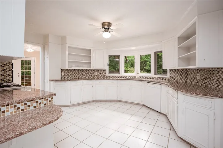 A well-lit kitchen boasts ample counter space, a bay window, and classic white cabinetry.
