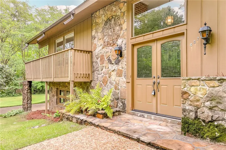 A stone and wood facade welcomes guests to this charming residence with a covered balcony.