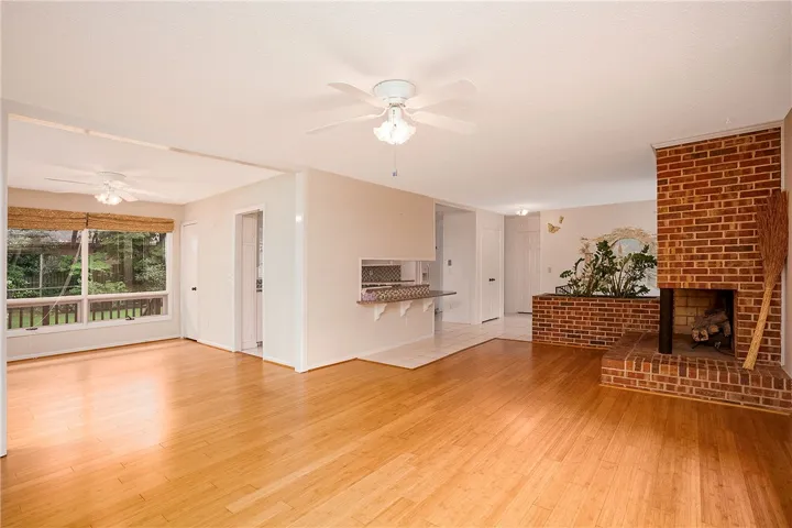 A well-lit living space features rich hardwood flooring and a classic brick fireplace.