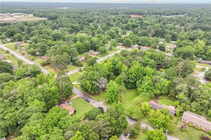 An aerial panorama reveals a verdant neighborhood with established trees and residential streets.