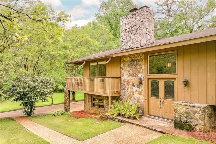 A striking stone chimney and wood siding complement the natural surroundings of this unique home.