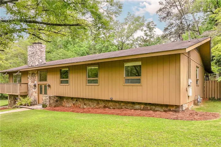 A charming exterior with stone detailing and a welcoming front entrance, framed by mature trees.
