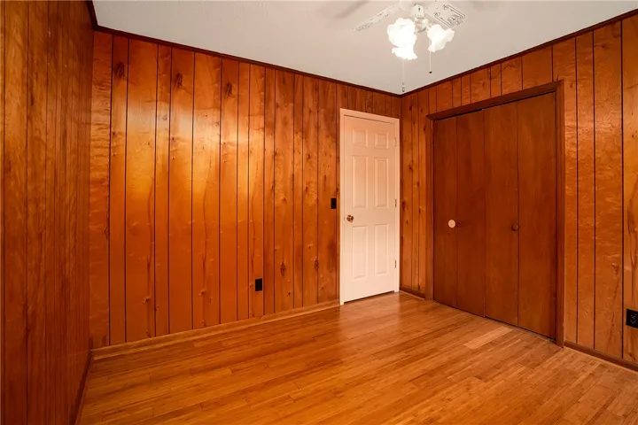 Warm wood paneling and bright flooring create a cozy, inviting bedroom space.