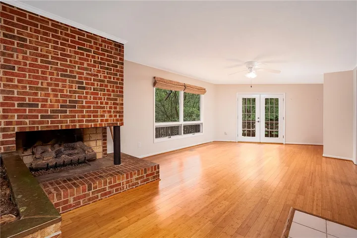 A welcoming living area featuring a brick fireplace and warm wood flooring.