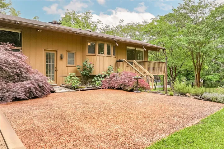 A vibrant green lawn and well-maintained shrubs frame this property's welcoming wooden deck.