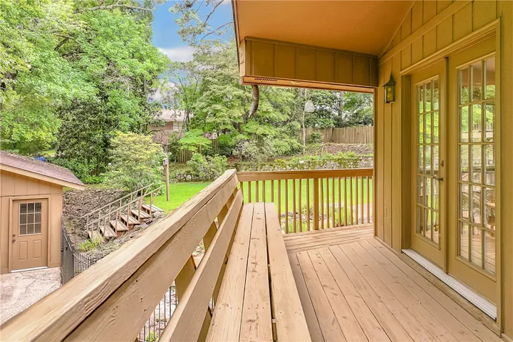 A spacious wooden deck with integrated seating overlooks a vibrant, treed landscape and terraced backyard.